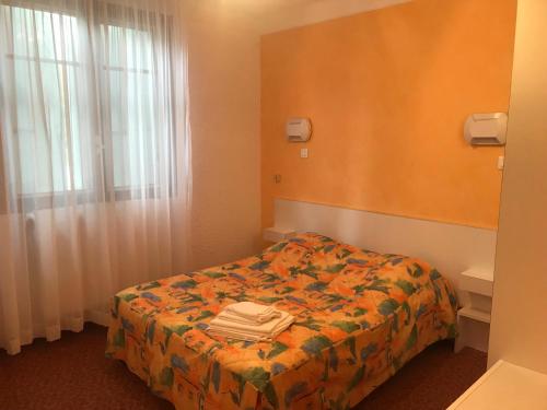 a hotel room with a bed and a window at Hotel Les Chênes in Sisteron