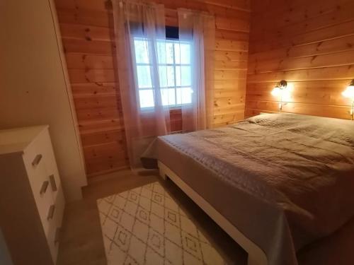 a bedroom with a bed in a wooden room at Velhonkieppi in Kittilä