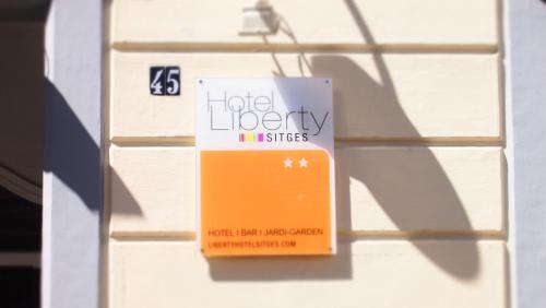 a sign hanging on the side of a building at Privat Hotel Liberty Sitges in Sitges