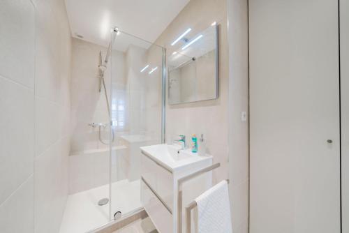La salle de bains blanche est pourvue d'un lavabo et d'une douche. dans l'établissement Brand new one bedroom heart of Cannes!!, à Cannes