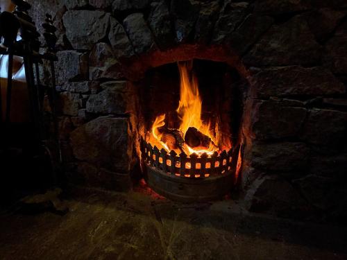 a stone fireplace with a fire in it at The Bridge Inn in Holmrook