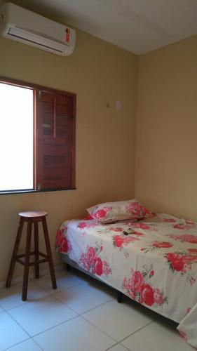 a bedroom with a bed and a stool and a window at Linda casa com 2 quartos, um com ar e outro com ventilador, e garagem in Parnaíba