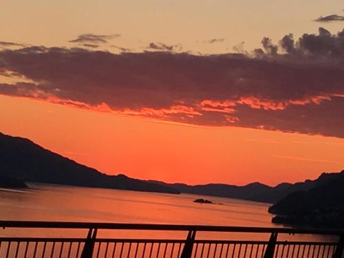 a sunset over a body of water with a fence at Skjerping gård in Lonevåg