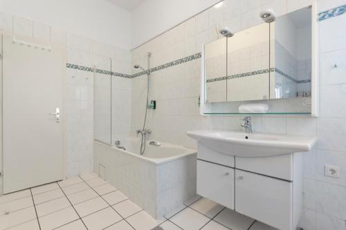 a white bathroom with a sink and a tub and a mirror at Flatista Homes - Old Town in Munich