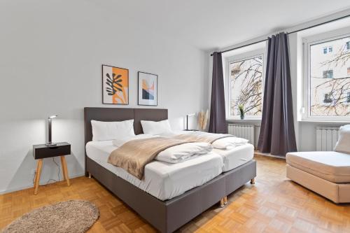um quarto com uma cama grande e uma cadeira em Flatista Homes - Old Town em Munique