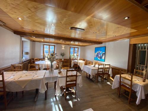 a dining room with tables and chairs with white tablecloths at Logis Hôtel Restaurant Au Lion Rouge in Bartenheim