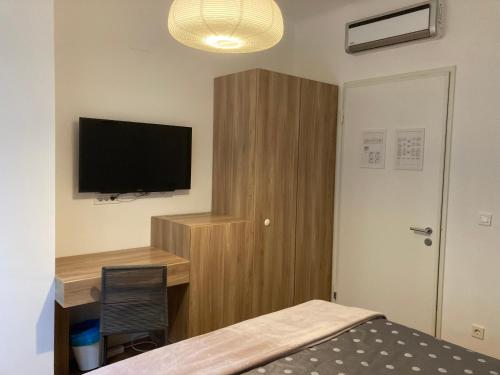 1 dormitorio con 1 cama y escritorio con TV en Twix rooms, en Liubliana
