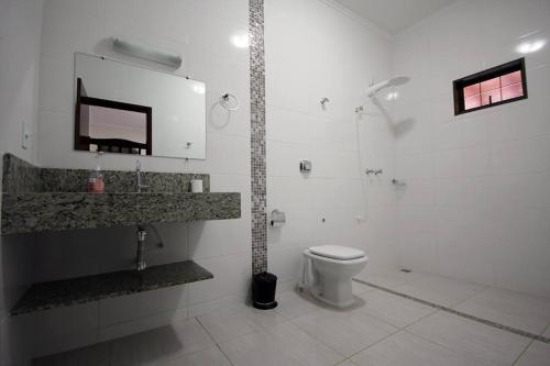 a white bathroom with a toilet and a sink at Recanto Vale do Sol in Olímpia