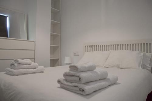 a white bed with towels on top of it at NOVAM Heredia in Málaga
