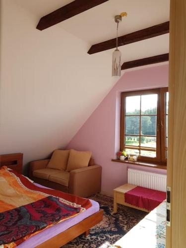 een slaapkamer met een bed, een bank en een raam bij Przytulne mieszkanie w sercu Kaszub in Wąglikowice