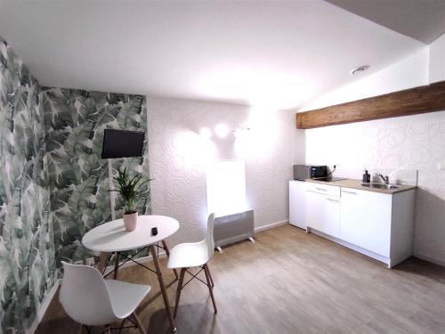 a room with a table and chairs and a kitchen at Les Meublés des Pierres Dorées - Gite de charme pour groupe in Theizé
