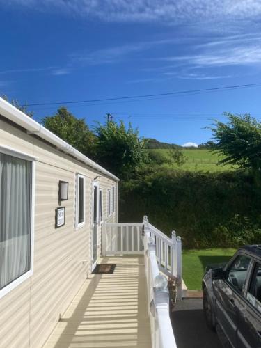 a house with a porch and a car parked next to it at Mollys Retreat pet friendly three bed caravan with small garden Newquay Bay Resort Quieter area of park in Newquay