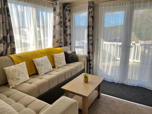 a living room with a couch and a table at Mollys Retreat pet friendly three bed caravan with small garden Newquay Bay Resort Quieter area of park in Newquay