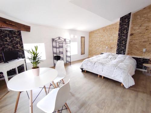 a bedroom with a bed and a table and chairs at Les Meublés des Pierres Dorées - Gite de charme pour groupe in Theizé