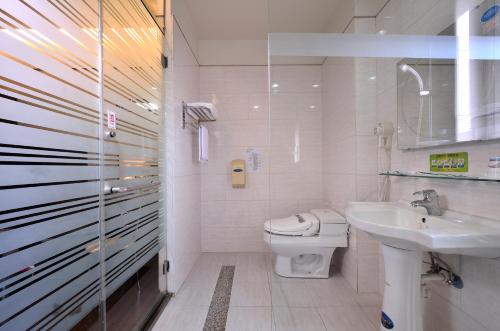 een witte badkamer met een toilet en een wastafel bij King Town Hotel in Luodong