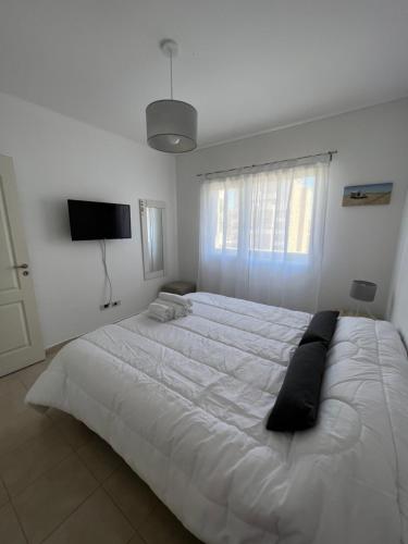 1 dormitorio blanco con 1 cama blanca grande y TV en Meseta en Puerto Madryn