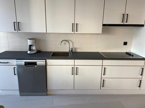 a kitchen with white cabinets and a sink and a dishwasher at Trendy & ruim appartement centum Oostende in Ostend