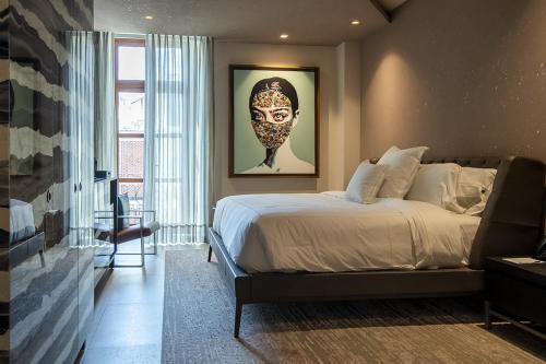 a bedroom with a bed and a picture of a mask at L Hotel Perla Boutique in Puebla