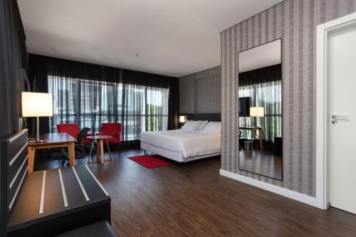 - une chambre d'hôtel avec un lit et un miroir dans l'établissement Hilton Garden Inn Praia Brava, à Itajaí