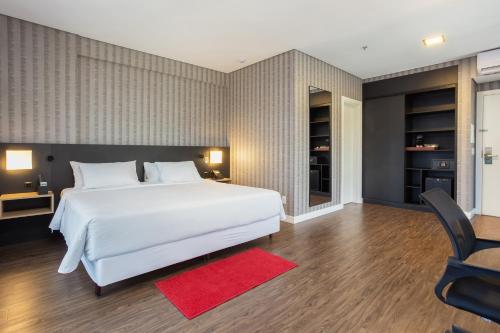 a bedroom with a large white bed and a red rug at Hilton Garden Inn Praia Brava in Itajaí