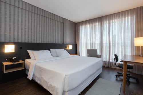 1 dormitorio con 1 cama blanca grande y escritorio en Hilton Garden Inn Praia Brava, en Itajaí