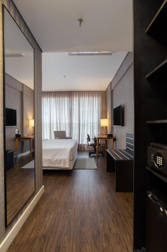 a hotel room with a bed and a large mirror at Hilton Garden Inn Praia Brava in Itajaí
