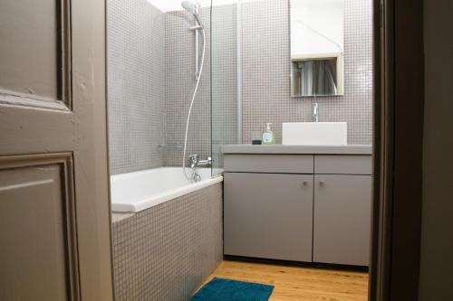 y baño con bañera, lavamanos y ducha. en Duplex dernier étage avec terasse à deux pas de la grand place en Bruselas