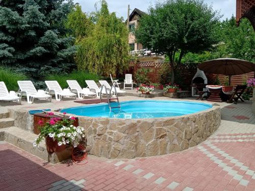 a swimming pool with white chairs and a stone wall at Petra Vendégház in Fonyód