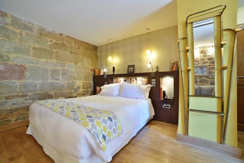 ein Schlafzimmer mit einem großen Bett und einer Steinmauer in der Unterkunft La Bastidie in Noailhac