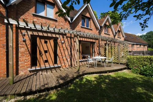 a brick house with a deck with a table and chairs at Ashbrook Lets Apartments in Blewbury