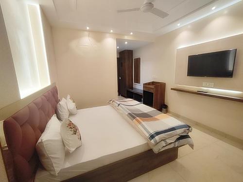 a bedroom with a bed and a flat screen tv at Hotel Luxuria in Ludhiana