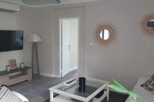 un salon avec une table basse en verre et un miroir dans l'établissement LA Maison D'AGEN, à Boé