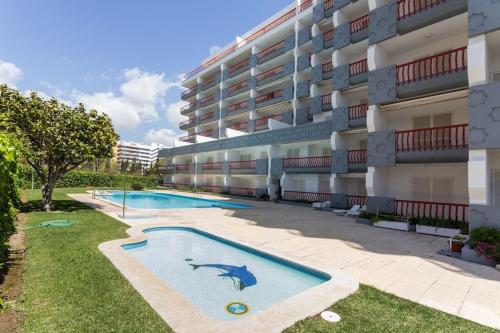 un immeuble avec une piscine devant un immeuble dans l'établissement Tivoli Apt8 with Pool&Garage, à Vilamoura
