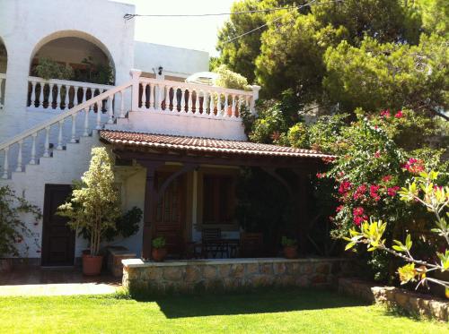 a house with a staircase and flowers in the yard at Studios Irene in Skala