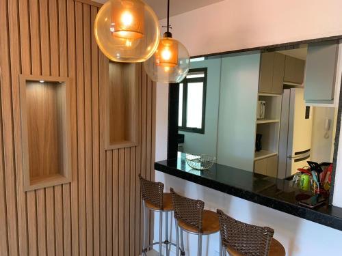 a kitchen with a bar with chairs and a mirror at Anjos Beach in Arraial do Cabo