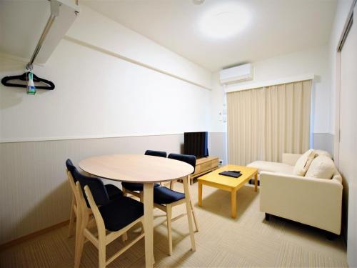 sala de estar con mesa, sillas y sofá en Land-Residential Hotel Fukuoka - Vacation STAY 81846v en Fukuoka