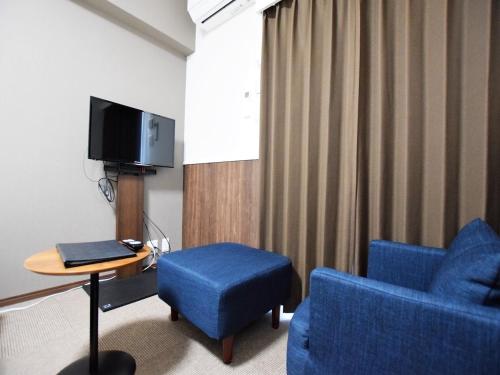 Land-Residential Hotel Fukuoka - Vacation STAY 81863v في فوكوكا: غرفة بها كرسي أزرق وطاولة وتلفزيون