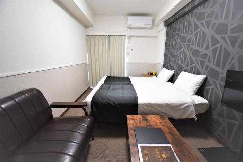 um quarto de hotel com uma cama e um sofá em Land-Residential Hotel Fukuoka - Vacation STAY 81837v em Fukuoka
