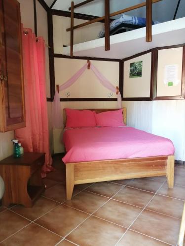 a bedroom with a bed with a pink bedspread at Cabañas Mountain River Lake Inn in Nueva California