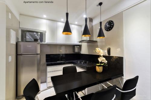 a kitchen with a black counter and black chairs at Apto 2Q com varanda no Ed Maximum Home in Natal
