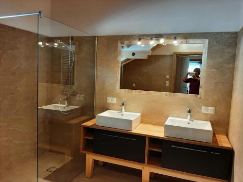 eine Person, die ein Bild von einem Badezimmer mit zwei Waschbecken macht in der Unterkunft Ferienwohnung Leni in Altaussee