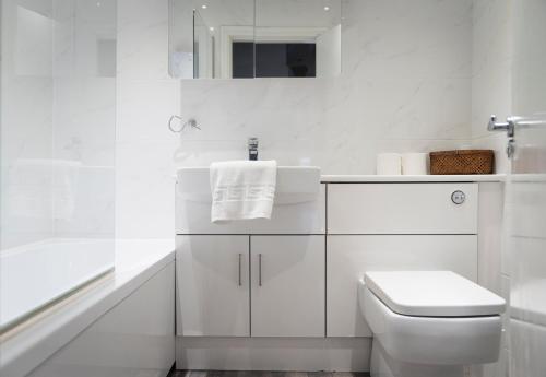 a white bathroom with a toilet and a sink at Cornerhouse Apartments Llandudno in Llandudno