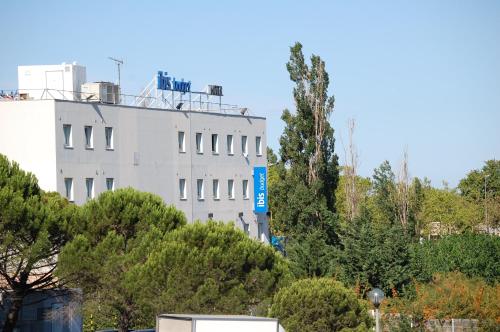 a white building on top of a hill with trees at Ibis Budget Marseille Vitrolles in Vitrolles