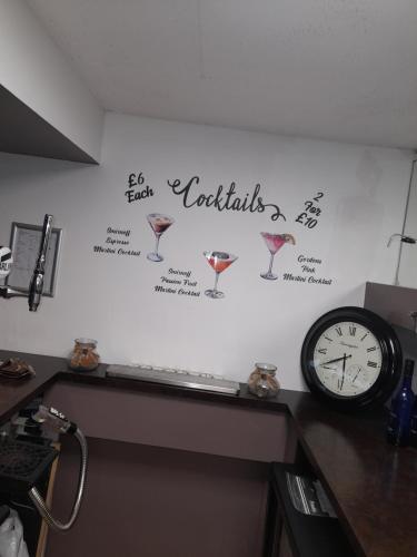 a wall with a clock and wine glasses on it at The Avenue Club and Lodge in Birmingham