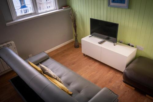 a living room with a couch and a flat screen tv at Apartment 4, Cornerhouse Apartments in Llandudno