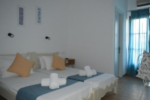 a bedroom with two white beds and a window at Pansion Katerina in Skiathos