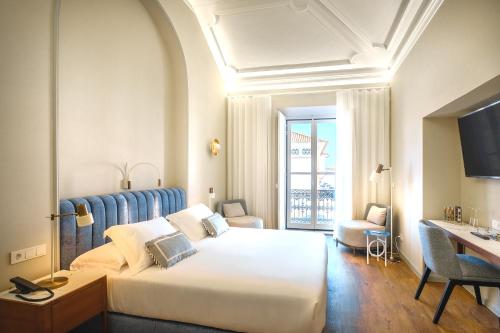 a hotel room with a large bed and a desk at MouraSuites Hotel in Évora