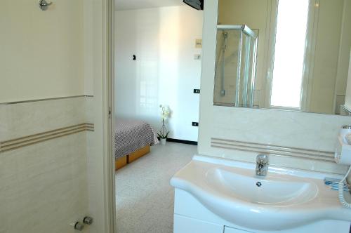 a white bathroom with a sink and a mirror at Hotel Marbella in Cervia