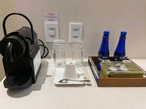 a table with bottles of water and a box of glasses at Golden Lis Hotel Boutique in Goiânia