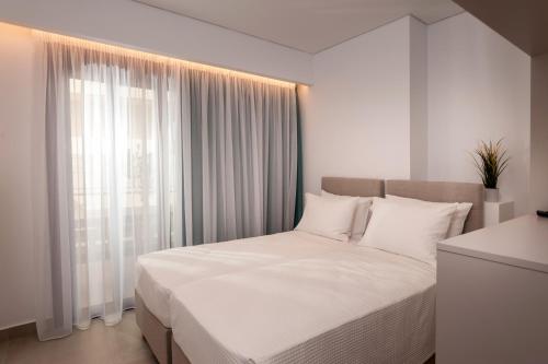 a bedroom with a bed with white sheets and a window at Thyme Sea View Apartments by 8essentially in Souda